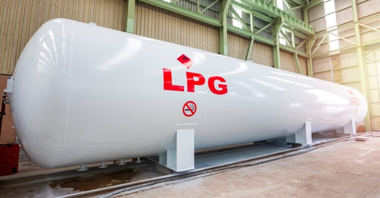 A large cylindrical storage tank laying on its side in a warehouse. On the tank, there are the letters "LPG" and flammable signs.